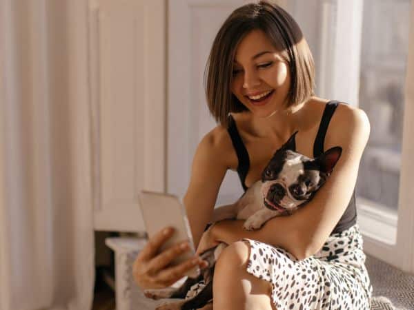 Woman holding a dog while on her phone